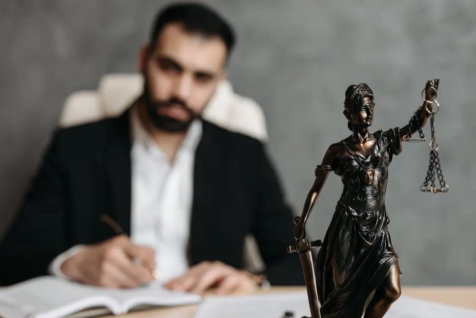 Abogado revisando un expediente con la estatuilla de la Justicia en primer plano